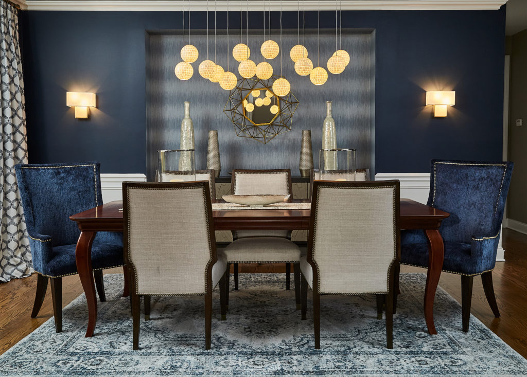 The drop pendant lighting in this transitional blue dining room contrast beautifully against the dark walls.